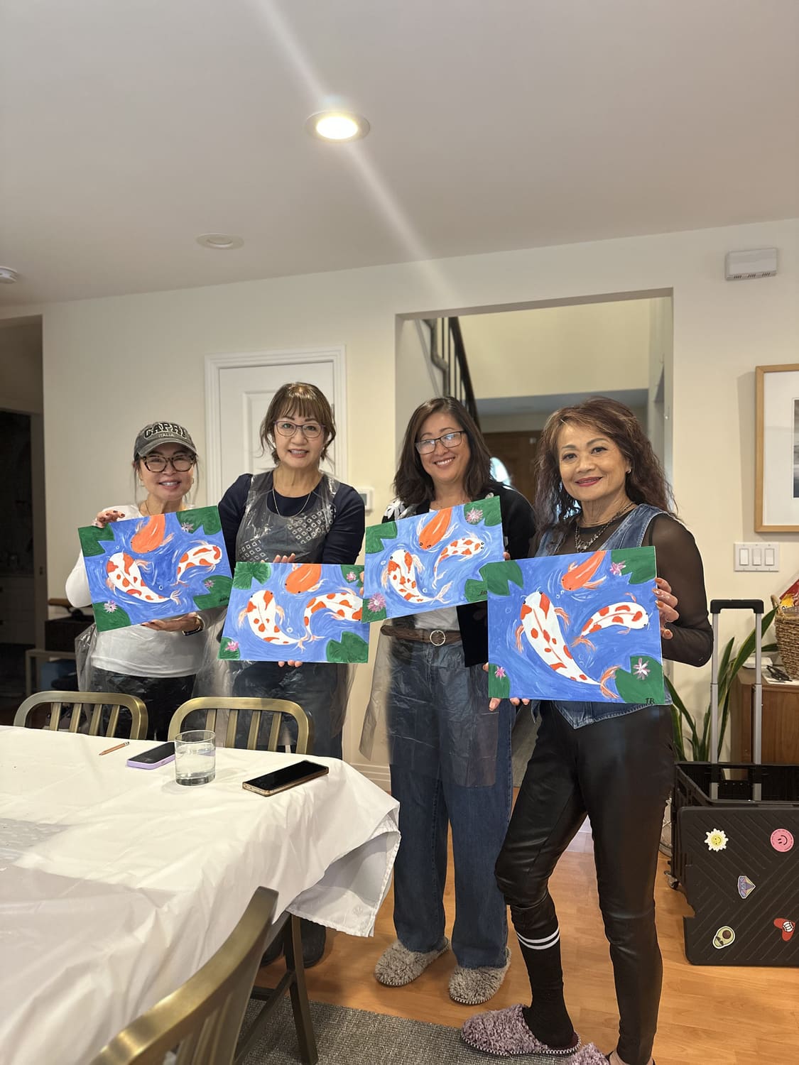 Four guests holding up the koi paintings they finished together