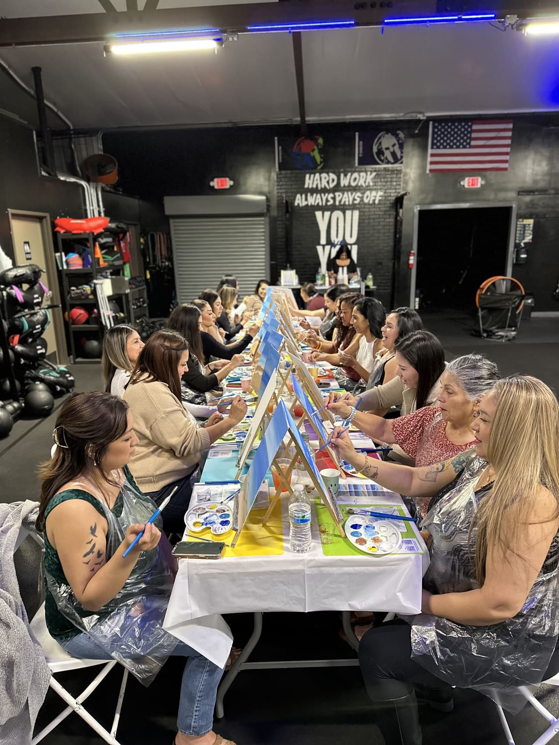 A large company group painting at one long table