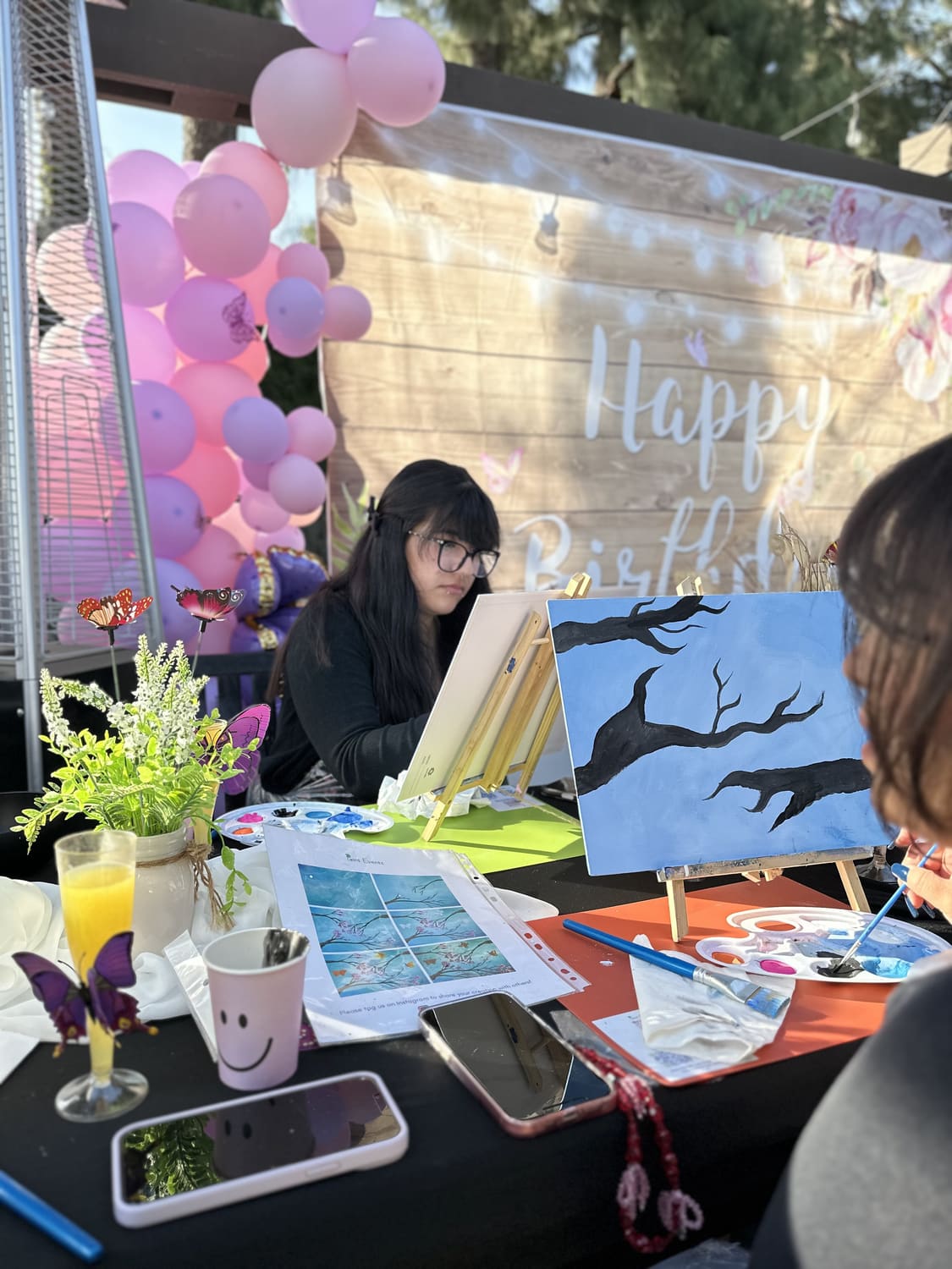 A guest painting beneath a balloon arch at a birthday celebration