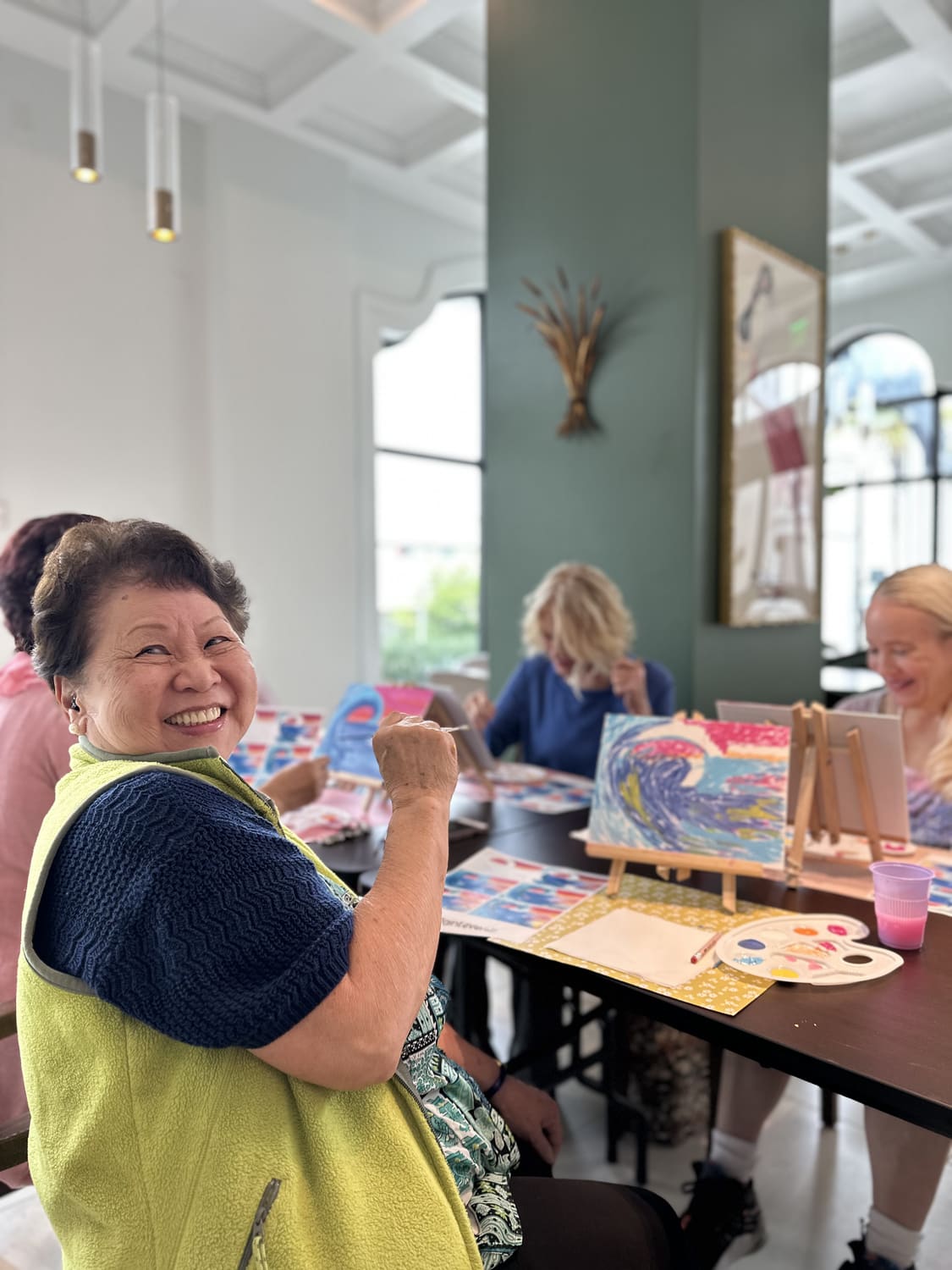 A resident smiling over her painting during a community centre session