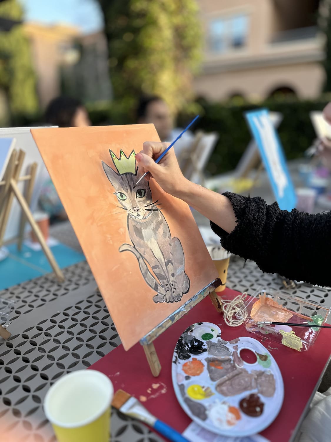 A guest painting a portrait of a cat wearing a crown