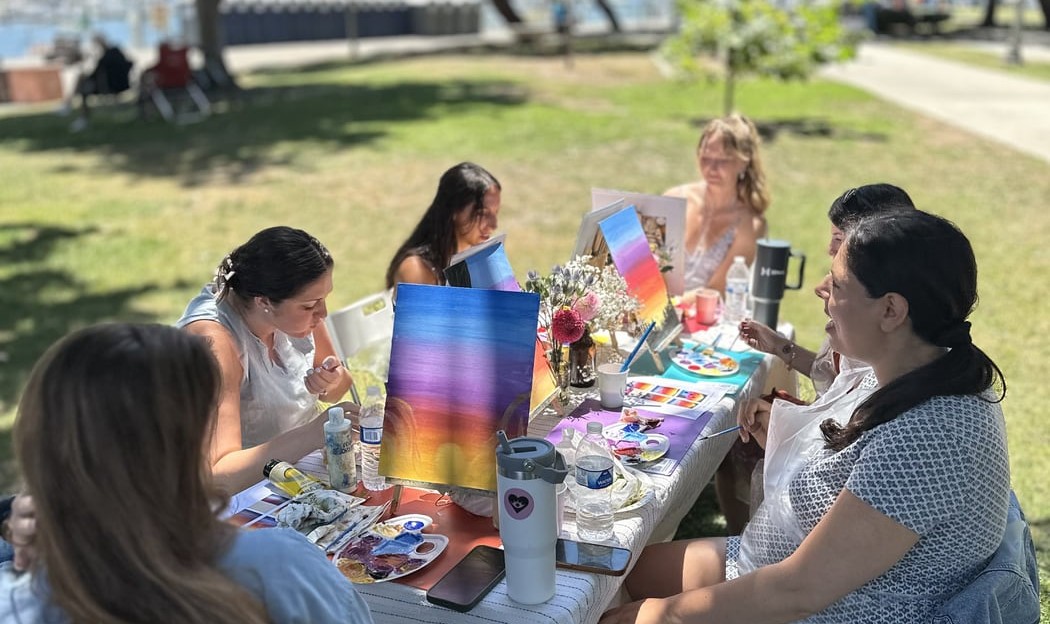 Guests painting colourful canvases together at an outdoor table